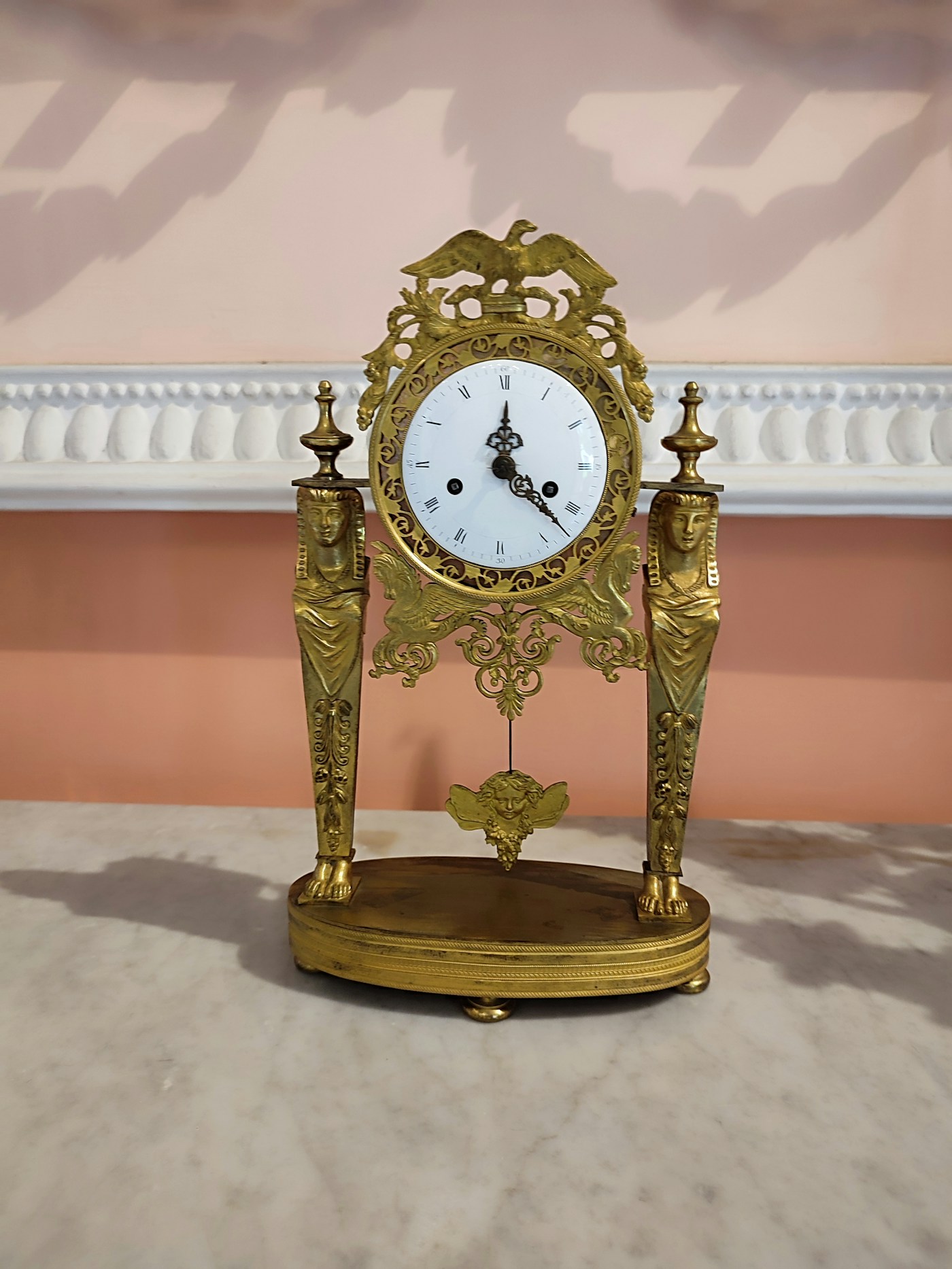 Antique bronze Empire mantel clock with caryatids and gilded ornaments