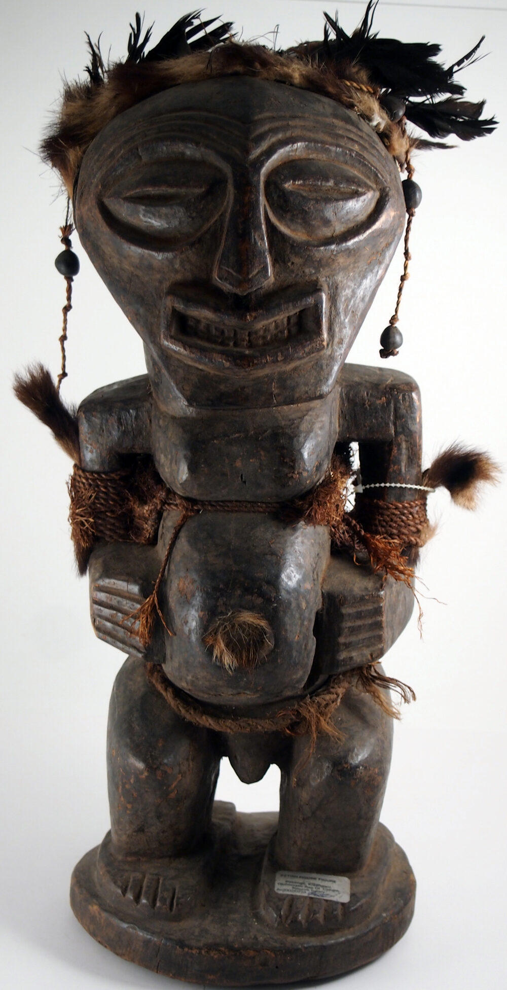Songye-Kraftfigur (nkishi) aus der Demokratischen Republik Kongo, aus geschnitztem Hartholz mit Federn, Fasern, Perlen, Leder und Fell, vom kantigen, magisch aufgeladenen Typ, den Sammler regelmäßig mit der gerundeten, höfischen Skulptur der benachbarten Luba verwechseln.