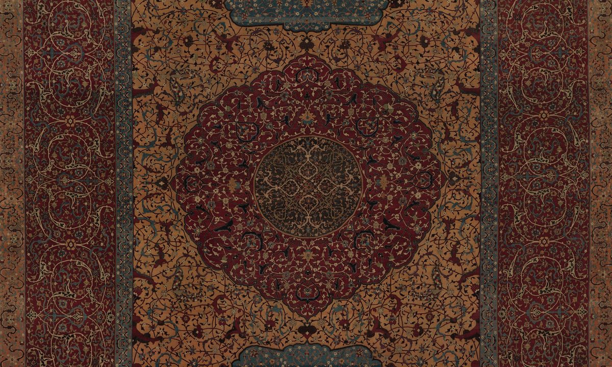 Détail d'un grand tapis persan avec un médaillon central rouge et polylobé sur un champ ocre couvert de rinceaux, avec des bordures rouges et bleues